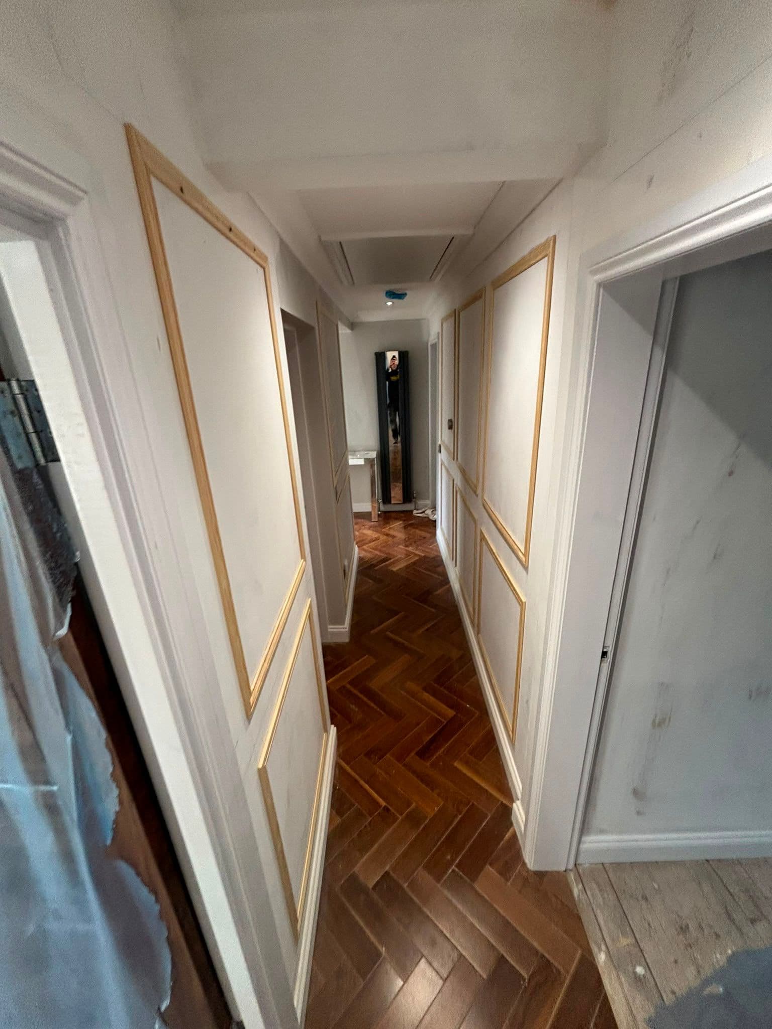 Wall panelling and wainscoting fitted in a hallway with herringbone flooring